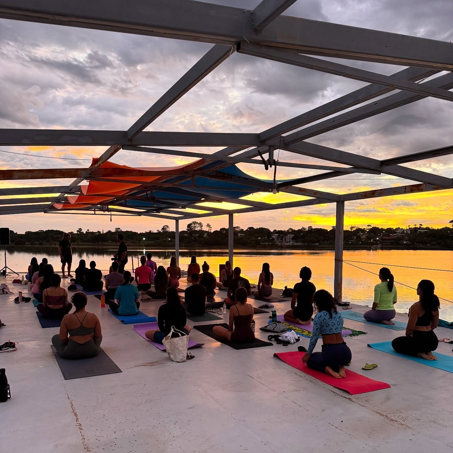 Yoga ao pôr do sol no deck sobre o lago com a comunidade Adrena
