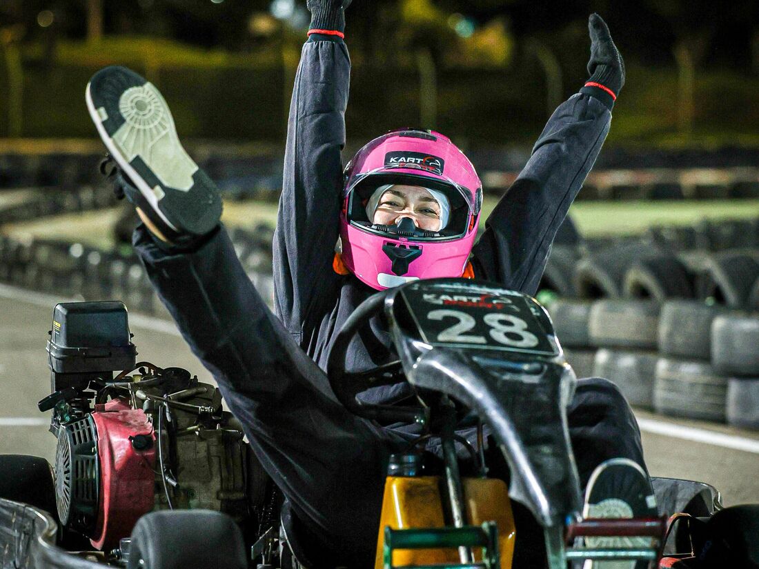 Pilota comemorando dentro do kart, braços e pernas para o alto