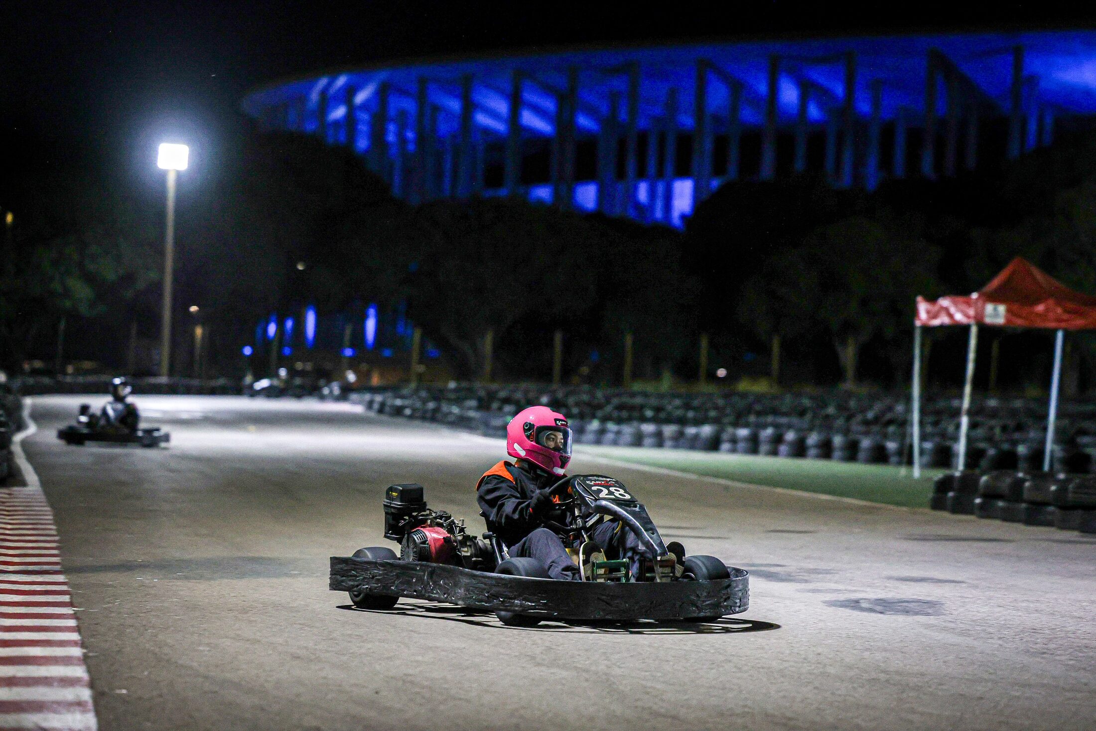 Kart na pista à noite, com o Mané Garrincha iluminado de azul ao fundo