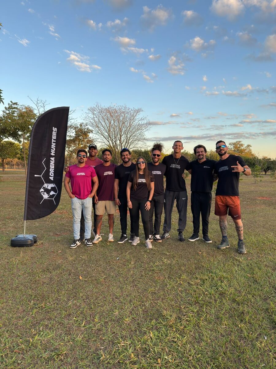 A comunidade do Adrena Hunters reunida ao pôr do sol, camisetas da marca e a bandeira do Adrena